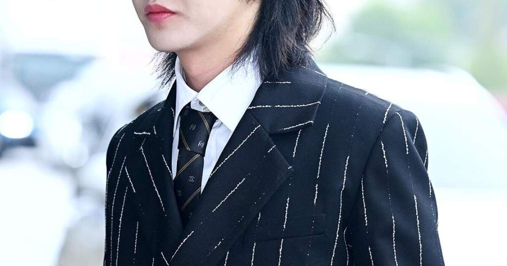 Renjun NCT DREAM mengenakan jas pinstripe hitam dan topi silinder di bandara