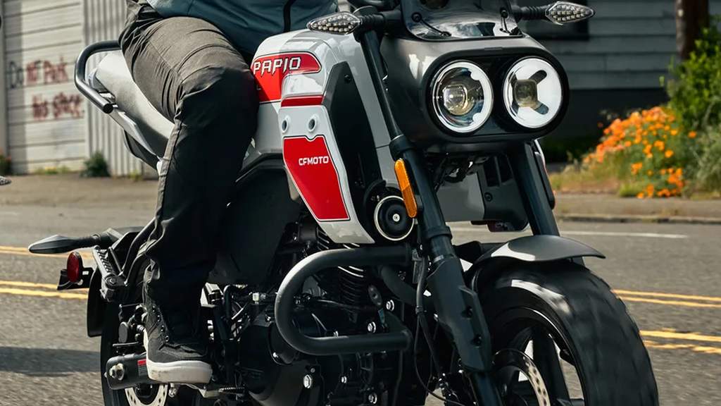 Motor mini scrambler CFMoto Papio CL berwarna putih dan hitam dengan ban tahu.