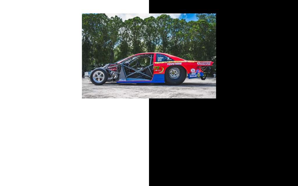 Mobil drag AEM Honda Civic dengan balutan warna merah dan biru di tempat lelang.